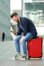 Middle aged man sitting on suitcase using mobile phone Royalty Free Stock Photo