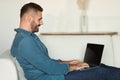 middle aged man smiles while working remotely on laptop indoors Royalty Free Stock Photo