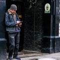 Middle Aged Man Standing In A Pub Doorway Using His Mobile Phone Or smartphone