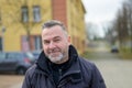 Middle-aged man standing in a town square looking at camera