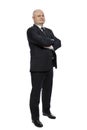 A middle-aged man in a strict black suit stands with his arms crossed over his chest. Full height. Isolated on white background. Royalty Free Stock Photo