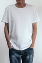 Middle-aged man with stubble in a white T-shirt and jeans on a gray background. White t-shirt template. Foreground Royalty Free Stock Photo