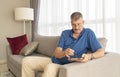 Middle aged man with a tablet on his sofa