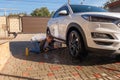 A middle-aged man teaches children of boys 4 and 10 years old to wash a car in the yard of his house on a summer sunny day. 2019. Royalty Free Stock Photo