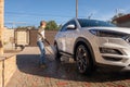 A middle-aged man teaches children of boys 4 and 10 years old to wash a car in the yard of his house on a summer sunny day. 2019. Royalty Free Stock Photo