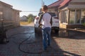 A middle-aged man teaches children of boys 4 and 10 years old to wash a car in the yard of his house on a summer sunny day. 2019. Royalty Free Stock Photo