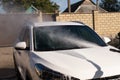 A middle-aged man teaches children of boys 4 and 10 years old to wash a car in the yard of his house on a summer sunny day. 2019. Royalty Free Stock Photo