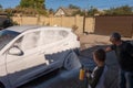 A middle-aged man teaches children of boys 4 and 10 years old to wash a car in the yard of his house on a summer sunny day. 2019. Royalty Free Stock Photo