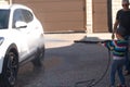 A middle-aged man teaches children of boys 4 and 10 years old to wash a car in the yard of his house on a summer sunny day. 2019. Royalty Free Stock Photo