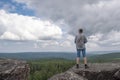 A middle-aged man at the top of the mountain enjoys a stunning view of the hilly valley. Freedom and goal achievement