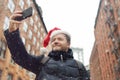 Middle aged man tourist in Santa Claus hat takes selfie on street near the Manhattan Bridge in New York City on Christmas Eve. Royalty Free Stock Photo