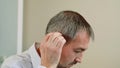 A middle aged man tries on a hearing aid.