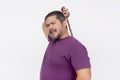 A middle aged man using a backscratcher to scratch and relieve an itch on his upper back. Looking satisfied. Isolated on a white Royalty Free Stock Photo