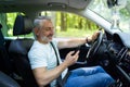 Middle aged man using a smart phone while driving a car in the street Royalty Free Stock Photo