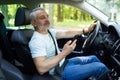 Middle aged man using a smart phone while driving a car in the street Royalty Free Stock Photo