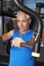 Middle Aged Man Using Weights Machine In Gym