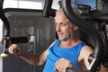 Middle Aged Man Using Weights Machine In Gym