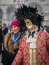 A middle-aged man in a vintage costume with a lace collar, wearing a carnival mask