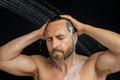 Middle aged man washing hair in bath. Guy bathing shower head in bathtub. Face in foam in shower. Bathing man taking Royalty Free Stock Photo
