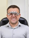Middle-aged man wearing glasses for eye exam in ophthalmologist's office.