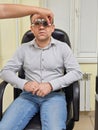 Middle-aged man wearing glasses for eye exam in ophthalmologist's office.