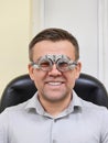 Middle-aged man wearing glasses for eye exam in ophthalmologist's office.