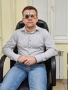 Middle-aged man wearing glasses for eye exam in ophthalmologist's office.