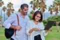 Middle-aged man and woman looking into the laptop screen outdoors Royalty Free Stock Photo