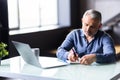 Middle-aged man working from home office on laptop Royalty Free Stock Photo