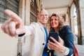 A middle aged mature couple pointing and watching the location on a gps app using a cellphone on a romantic journey trip