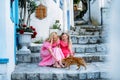 Middle aged millenial woman mother and blonde teenage girl daughter playing with cat on the medieval street with white houses in o