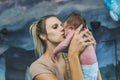 Middle-aged millennial caucasian blonde mother in casual clothing holding up her little infant baby boy in diaper and Royalty Free Stock Photo