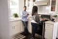 Middle aged African American  couple standing together in the kitchen preparing food on the hob using a recipe on a tablet compute Royalty Free Stock Photo