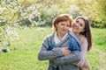 Middle-aged mother and her daughter hugging in blooming garden Royalty Free Stock Photo