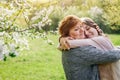 Middle-aged mother and her daughter hugging in blooming garden Royalty Free Stock Photo