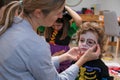 Mature woman painting her son's face in skeleton costume Royalty Free Stock Photo