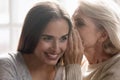 Middle aged mother whispering secret to grown up daughter Royalty Free Stock Photo