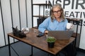 Middle aged older business woman in her fifties working on a laptop online drinking tea in the office, concept of Royalty Free Stock Photo