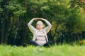 Older woman sits on the grass and doing sports exercises doing yoga Royalty Free Stock Photo