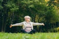 Older woman sits on the grass and doing sports exercises doing yoga Royalty Free Stock Photo