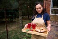 Pleasant multiethnic housewife holds a serving tray with freshly baked homemade cherry pies and refreshing berry compote