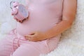 middle-aged pregnant woman holds alarm clock near her belly close-up, waiting for newborn, concept of prenatal contractions,