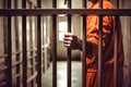 A middle-aged prisoner in an orange uniform sits in a prison cell. The criminal serves his sentence in a prison cell. A prisoner Royalty Free Stock Photo