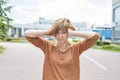 A middle-aged redhead woman in casual clothes stands on the street covering her ears Royalty Free Stock Photo