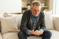 Middle aged senior man holding medical pills sitting on couch at home. Mature old senior grandfather taking medication Royalty Free Stock Photo