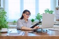 Middle-aged serious woman working at computer laptop in home office Royalty Free Stock Photo