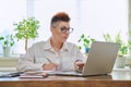 Middle-aged serious woman working at computer laptop in home office Royalty Free Stock Photo