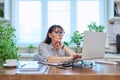 Middle-aged serious woman working at computer laptop in home office Royalty Free Stock Photo