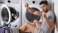 Middle aged single man with laundry basket and dirty clothes near washing machine at home. Millennial man putting Royalty Free Stock Photo