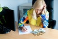 Middle-aged thoughtful woman counting euro money and takes notes at a desk in the home office Royalty Free Stock Photo